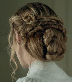 a woman with braids in her hair looking into the distance while wearing a white shirt