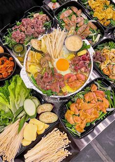 an assortment of food items displayed in trays on a buffet table with chopsticks