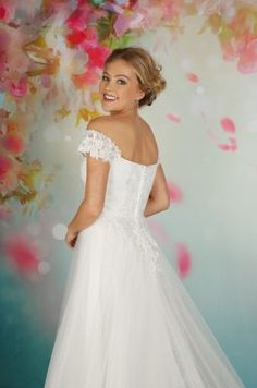 a woman in a white wedding dress standing next to a floral wall with flowers on it