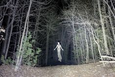 a woman is walking through the woods at night