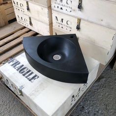 a black sink sitting on top of a white box next to some pallet boxes