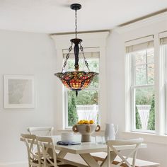 a dining room table with four chairs and a chandelier hanging from the ceiling