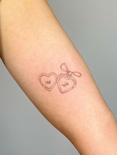 a woman's arm with two hearts and a bow tattoo on the left side