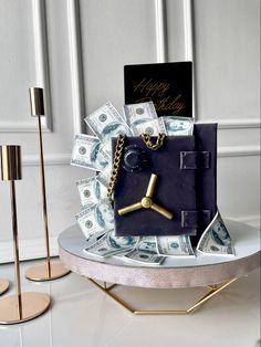 a clock made out of money with a gold chain and key attached to it, sitting on top of a table