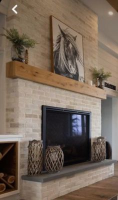 a living room with a fireplace and pictures on the wall above it, along with two vases filled with flowers