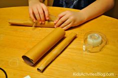 a child rolling out rolled up dough on top of a wooden table next to two rolls of wax paper