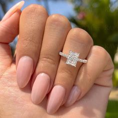 a woman's hand holding a ring with a diamond on it and the middle finger