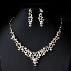 a necklace and earring set with pearls on a mannequin neckline in front of a black background