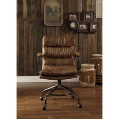 a brown leather office chair sitting in front of a wooden wall with pictures on it