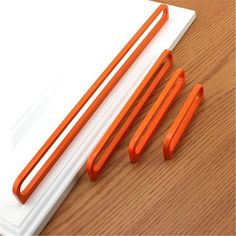 three orange scissors sitting on top of a piece of paper next to two white papers