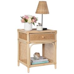 a wicker night stand with a lamp and flowers on the side table next to it