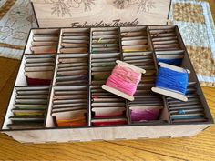 a wooden box filled with lots of different colored thread