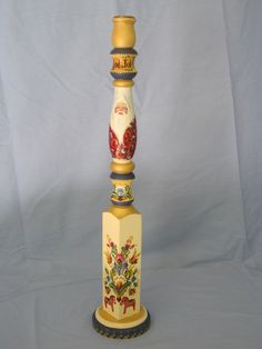 a tall yellow and red vase sitting on top of a white table next to a blue wall