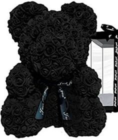 a large black teddy bear with roses on it's chest and an open box in the background