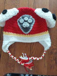 a crocheted hat with a dog's paw on it sitting on top of a wooden floor