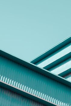 an airplane is flying over the top of a building with green metal roofing and blue sky in the background