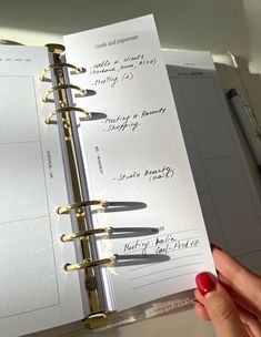 a hand holding an open planner book with writing on it