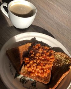 a plate topped with toast and beans next to a cup of coffee