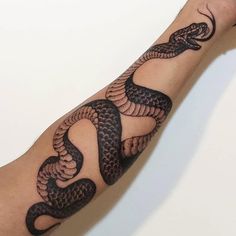 a man's arm with a black and grey snake tattoo on it, while he is holding his hand up to the camera