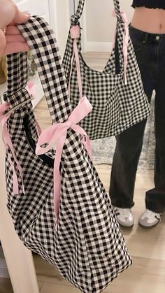 a woman is holding two bags with pink bows on them, and another person has their leg in the background