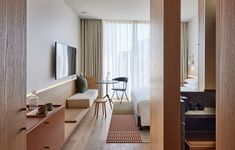 a hotel room with a bed, desk and television on the wall next to it