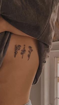 the back of a woman's stomach with three small flowers on it