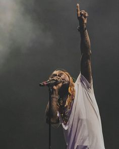 a man standing on top of a stage holding his hand up in the air while singing into a microphone