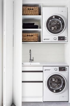 a washer and dryer in a white laundry room with open shelve