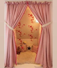 a bedroom with pink curtains and stars on the wall