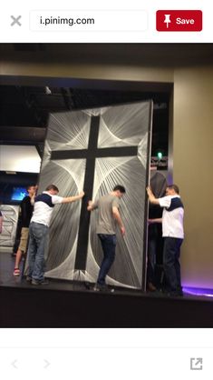 some people are standing in front of a cross on a stage and one person is holding the cross