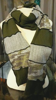 a green and white scarf sitting on top of a mannequin