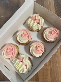 six cupcakes in a box with pink and white frosting on the top