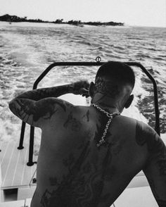 a man with tattoos on his back sitting in a boat