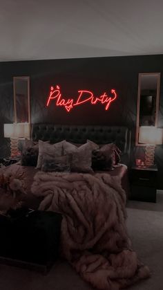 a bed room with a neatly made bed and a neon sign