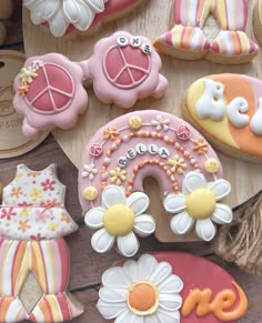 some decorated cookies are sitting on a wooden board with flowers and other items around them