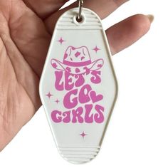 a hand holding a keychain with the words let's go girls on it