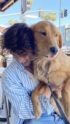 a woman sitting in a chair holding a large brown dog on her lap and smiling at the camera