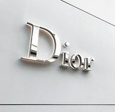 the letters d and f are made out of silver metal on a white building wall