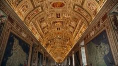 people are walking down an ornate hallway in a building with many paintings on the walls