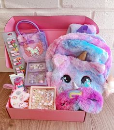 a pink and blue unicorn backpack sitting on top of a wooden floor next to other items