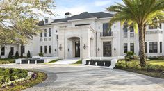 a large white house with palm trees in the front yard