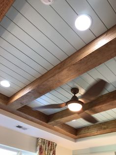 a ceiling fan is hanging from the ceiling in a room with white walls and wood beams