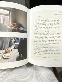 an open book with writing on it and two people sitting at a table in the background