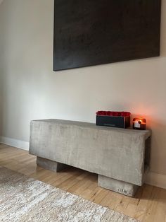 a concrete bench with candles on it in front of a painting and carpeted floor