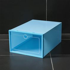 a blue box sitting on top of a tiled floor next to a black tile wall