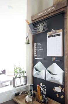 a blackboard with writing on it in the corner next to a desk and potted plants