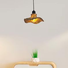 a lamp hanging from the ceiling above a bed in a room with white walls and wooden furniture