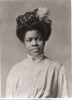 an old black and white photo of a woman with flowers in her hair, wearing a dress