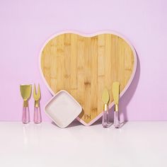 a heart shaped cutting board with utensils and spoons in front of it