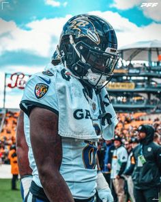 a football player is standing on the field with his hands in his pockets and wearing a helmet